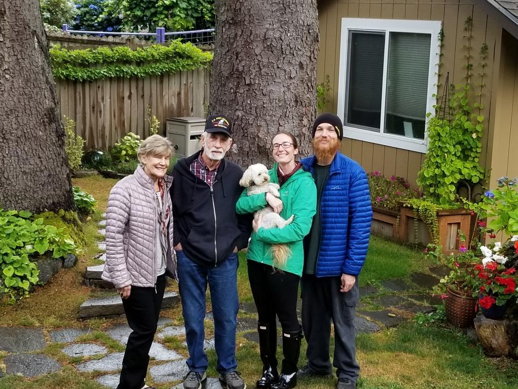 Tunstall holds a cute little white dog with her family in their backyard, smiling for a photo.