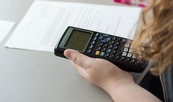 student working on math homework holding calculator