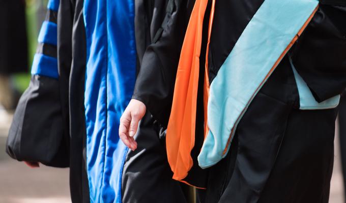 Two professors walking in doctoral gowns on campus